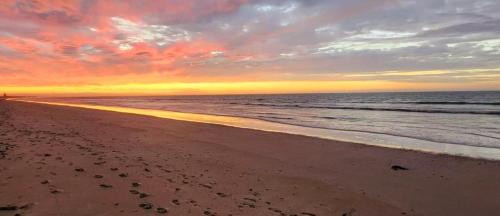 a sunset on a beach with footprints in the sand at Serenity in Velddrif