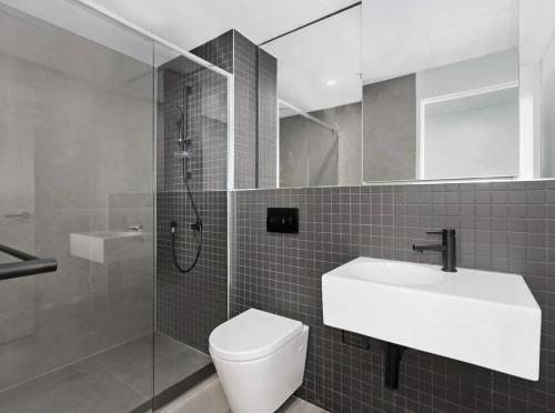 a bathroom with a toilet and a sink and a shower at Lakeside Apartment with Great Views in Belconnen