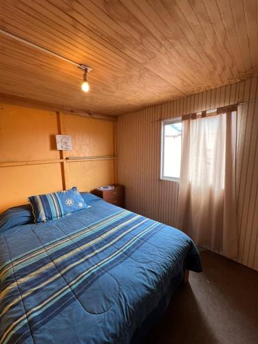 1 dormitorio con 1 cama con edredón azul y ventana en ¡Casa equipada para vacacionar!, en Viña del Mar