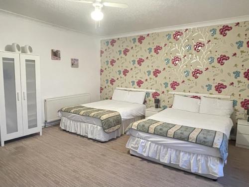 Duas camas num quarto com papel de parede floral em The Dolphin Hotel em Great Yarmouth