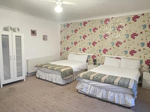 two beds in a room with floral wallpaper at The Dolphin Hotel in Great Yarmouth