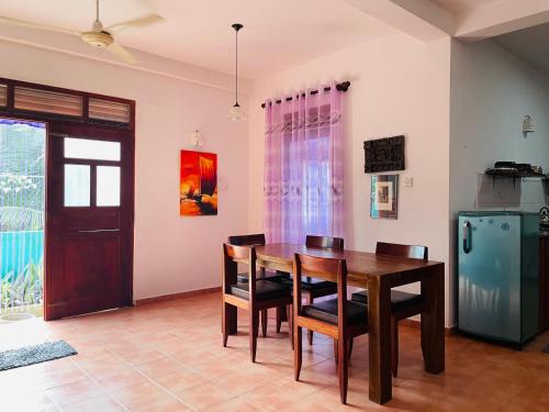 a dining room with a table and chairs and a refrigerator at White Villa in Unawatuna