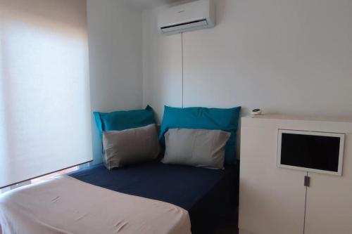 een kamer met een bed met blauwe kussens en een televisie bij Estudio en Envía Golf Bello Rincón Paz y Vistas in Vícar