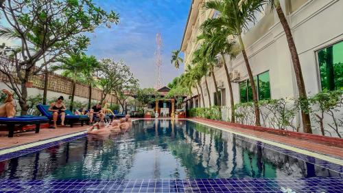 ein Pool in einem Hotel mit Leuten, die auf Stühlen im Wasser sitzen in der Unterkunft Harmony Indochine d'Angkor in Siem Reap