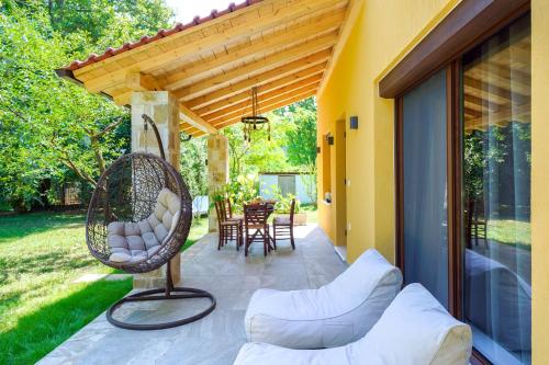 a patio with a wicker chair and a table at Natura Bungalows-Villa in Limenas