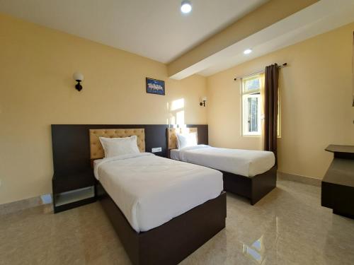een hotelkamer met 2 bedden en een raam bij Snow White Retreat Hotel& Restaurant in Gangtok