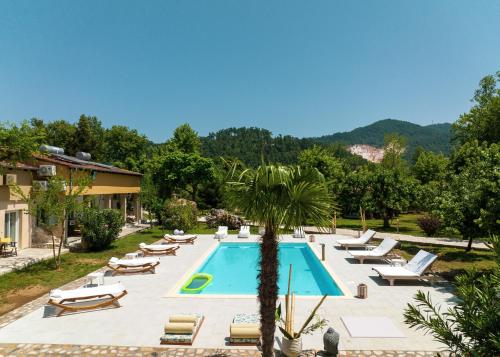 a pool at a resort with lounge chairs and a palm tree at Natura Bungalows-Villa in Limenas