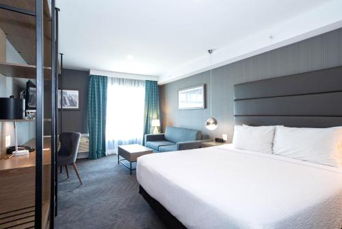 a hotel room with a bed and a chair at Sandman Signature Calgary Airport Hotel in Calgary
