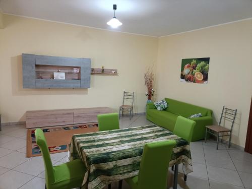 a living room with a table and green chairs at B&B Il Gabbiano in Reggio Calabria