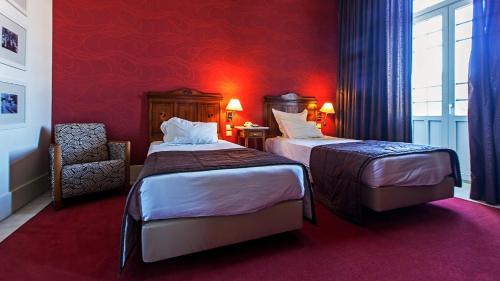 a hotel room with two beds and a chair at Curia Palace Hotel & Spa in Curia