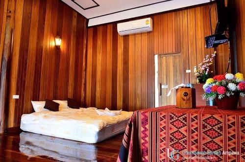 a bedroom with a bed in a wooden wall at บ้านสวนอุดมสวัสดิ์ อัมพวา in Amphawa