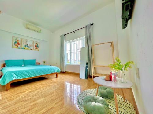 Schlafzimmer mit einem blauen Bett und einem Tisch in der Unterkunft NHÀ NGHỈ QUANG'S in Phú Vang