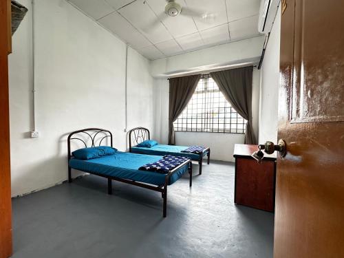 twee bedden in een kamer met een deur bij Jiaxin Dormitory - Puteri Wangsa 家馨旅舍 in Ulu Tiram