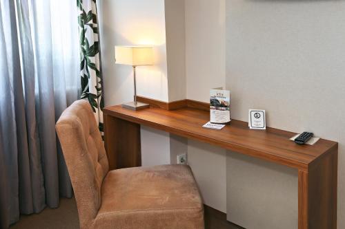 Zimmer mit einem Schreibtisch, einem Stuhl und einem Spiegel in der Unterkunft Hotel Vorderburg in Schlitz
