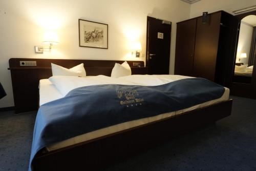 a hotel room with a bed with a blue blanket on it at Hotel Goldener Adler in Bautzen