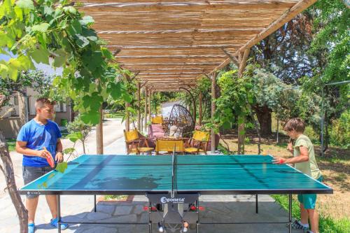 two people standing around a ping pong table at Natura Bungalows-Villa in Limenas
