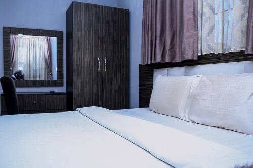 a bedroom with a white bed and a mirror at Mohouse Hotels and Apartments Mabushi in Abuja