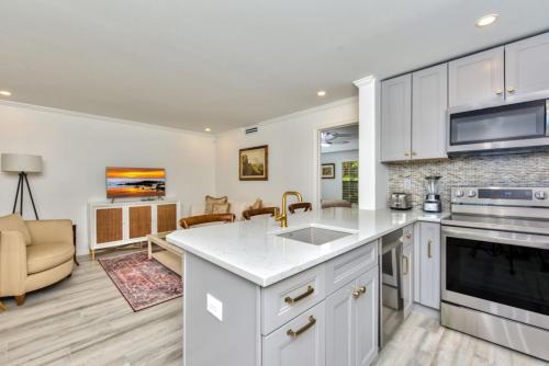 a kitchen with white cabinets and a living room at Le Malo Vacation Rental in Naples