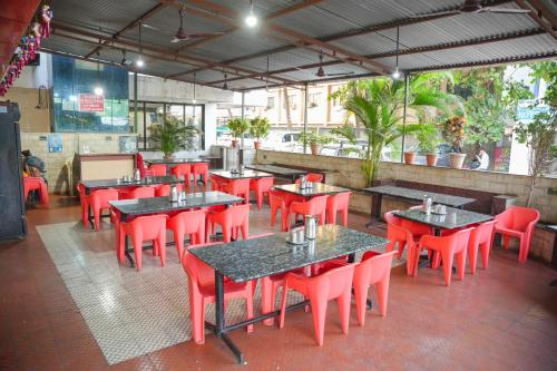 an empty restaurant with tables and red chairs at Hotel Sachidanand in Shirdi