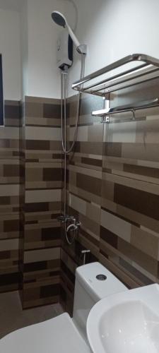 W łazience znajduje się toaleta, prysznic i umywalka. w obiekcie Lorraine Suites w mieście Borongan