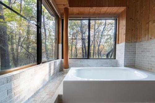 a bath tub in a room with windows at Ryojukukan Villa Nasukogen in Nasu
