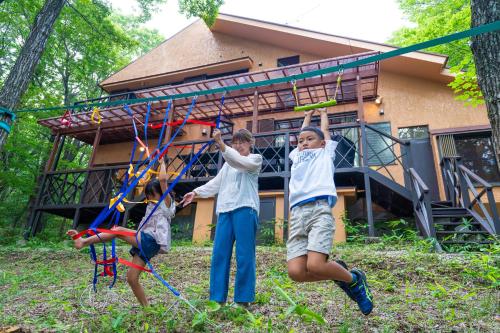 three children playing with kites in front of a house at Ryojukukan Villa Nasukogen in Nasu