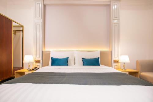 a bedroom with a large bed with two blue pillows at Cambana Poipet Hotel in Krong Poi Pet