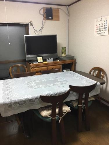 een kamer met een tafel met stoelen en een televisie bij Rumah Kyoto Yu in Shimmachidōri