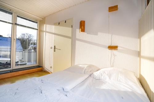 Cama blanca en habitación con ventana en Fewo Strandkrabbe, en Grömitz
