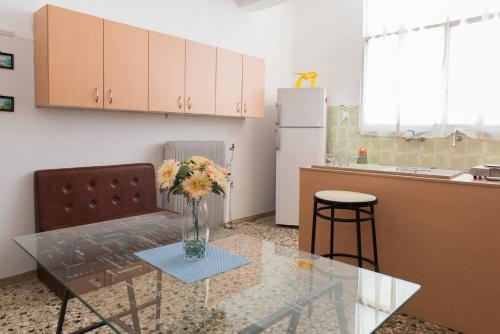 a kitchen with a glass table with a vase of flowers on it at HELLAS PALACE ROOMS balcony in Sparti