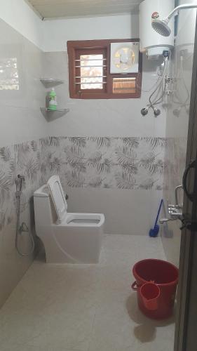 een badkamer met een wit toilet en een raam bij Coorg Milestone Homestay in Madikeri