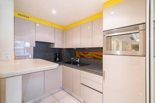 une cuisine avec des armoires blanches et un évier dans l'établissement Beautiful one bedroom two minute walk to Carlton Hotel, à Cannes