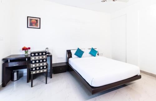 a bedroom with a bed next to a desk at Sanctum Suites Domlur Bangalore in Bengaluru