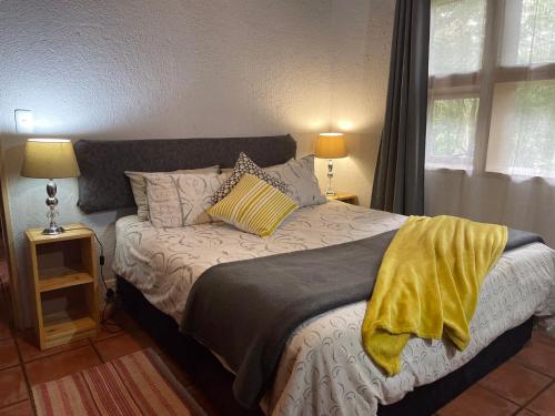 a bedroom with a bed with a yellow blanket on it at Sabie Stay in Sabie