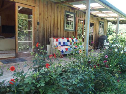 a porch of a house with a couch and flowers at Woodland eco retreat in Parapara 