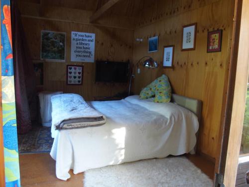 Woodland eco retreat في Parapara : غرفة نوم بسرير في غرفة خشبية