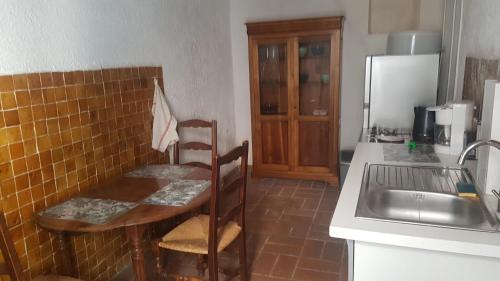 een keuken met een tafel, een wastafel en een koelkast bij Appartement médiéval au cœur du village de Lama in Lama