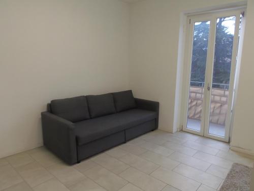 a black couch in a room with a sliding glass door at Apartaments and Rooms Claudia Augusta in Bolzano