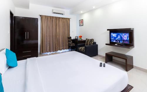 a hotel room with a bed and a flat screen tv at Sanctum Suites Domlur Bangalore in Bengaluru