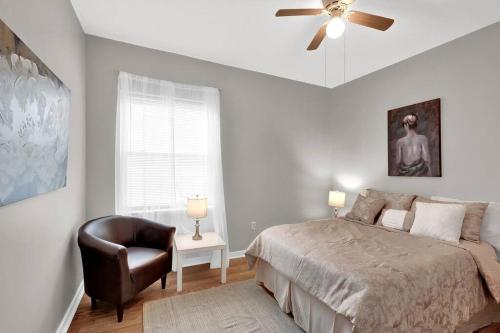 Prime Area In Philly - Large Lovely Apartment في فيلادلفيا: غرفة نوم بسرير وكرسي ومروحة سقف