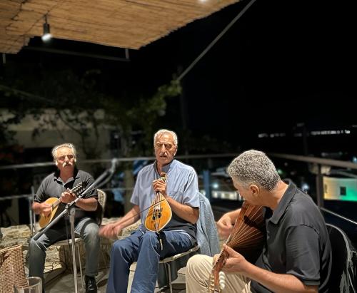 een groep mensen die in stoelen zitten en instrumenten bespelen bij Pyrgi Cretan Living & Spa in Pírgos