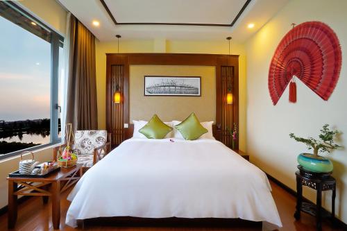 - une chambre avec un grand lit blanc et une fenêtre dans l'établissement Koi Resort & Spa Hoi An, à Hội An