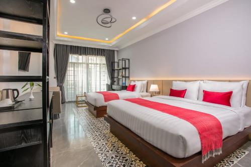 two beds in a hotel room with red pillows at Cambana Poipet Hotel in Krong Poi Pet