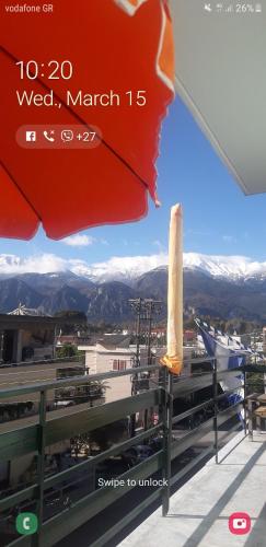 a red umbrella on a balcony with a view of mountains at HELLAS PALACE ROOMS balcony in Sparti