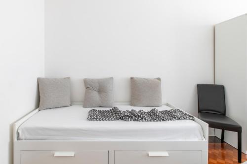 a white bed with a black chair and a mirror at LA MAR Apartment Spinea in Spinea