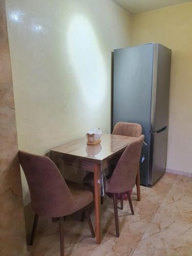 a table with chairs and a stainless steel refrigerator at Prima home 