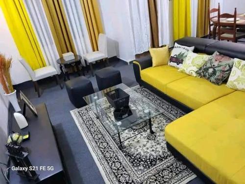 uma sala de estar com um sofá amarelo e uma mesa em Entrée personnelle fidjrossè plage em Cotonou