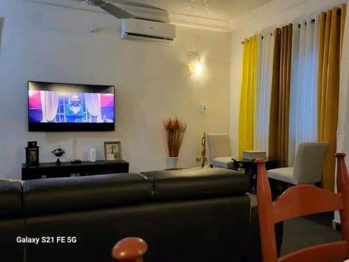 uma sala de estar com um sofá e uma televisão de ecrã plano em Entrée personnelle fidjrossè plage em Cotonou