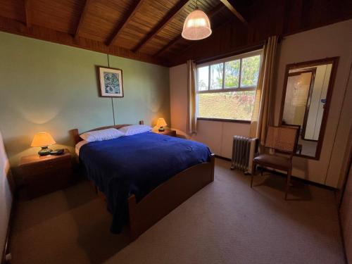 a bedroom with a blue bed and a window at Recanto Habacuque in Campos do Jordão