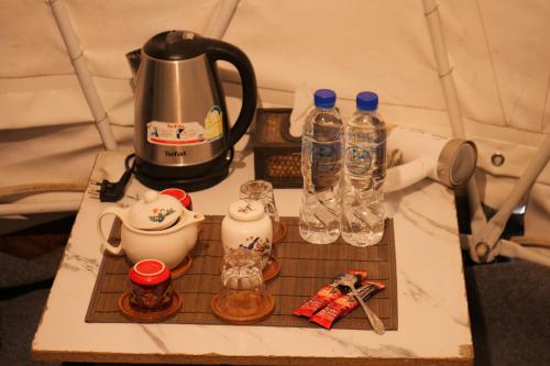 a tea kettle and two bottles of water on a counter at Dome tents Hedreung Rakthai camping in Ban Rak Thai